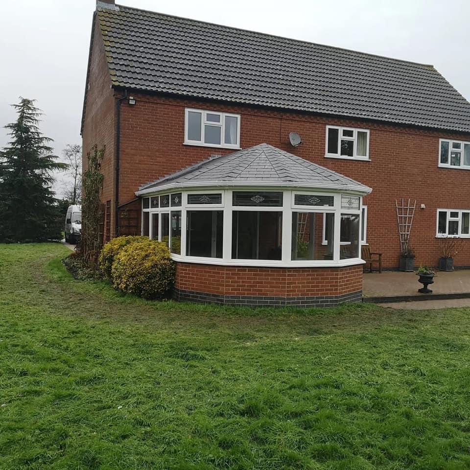 Tiled conservatory and house with garden and bushes