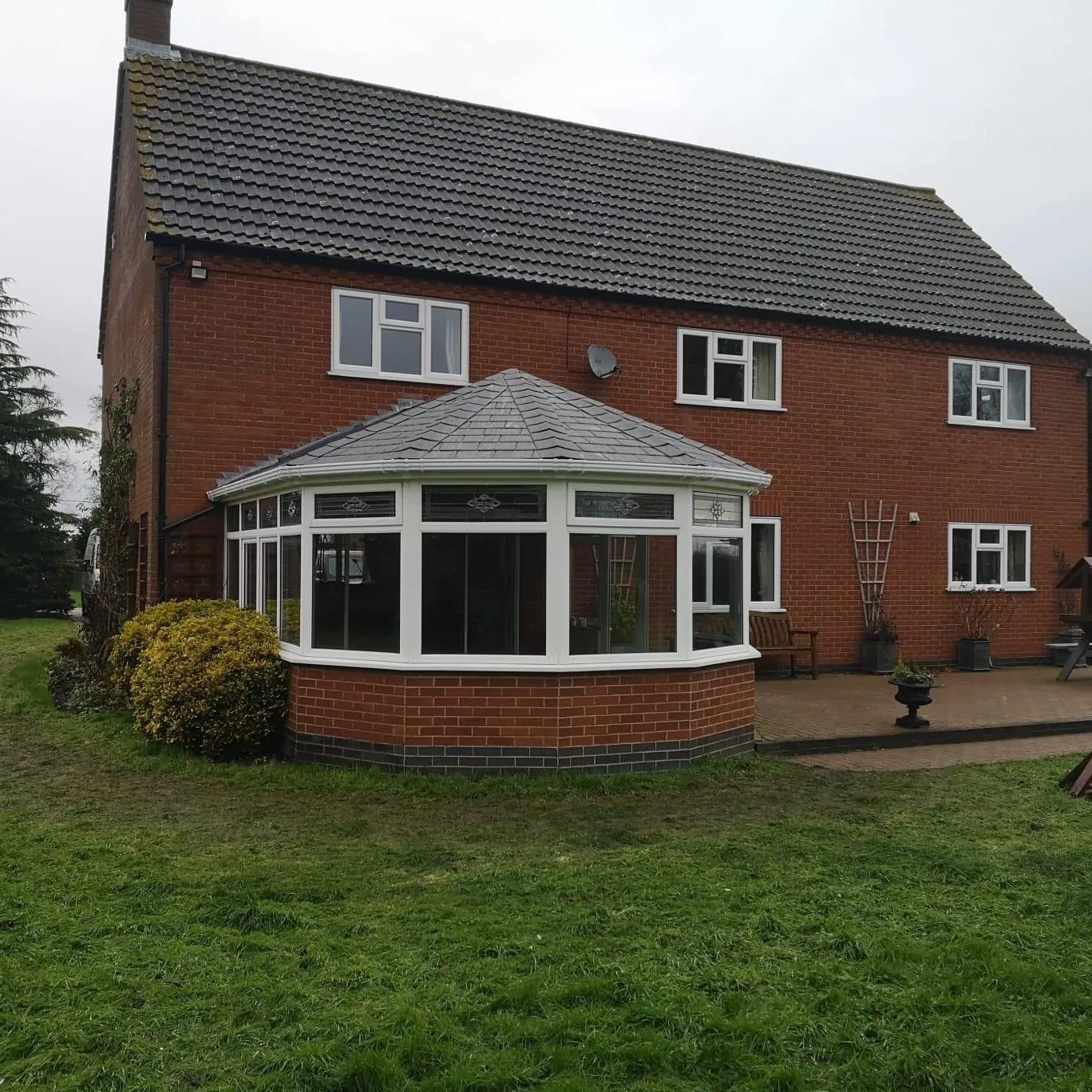 Outside view of tiled conservatory and house with garden and patio