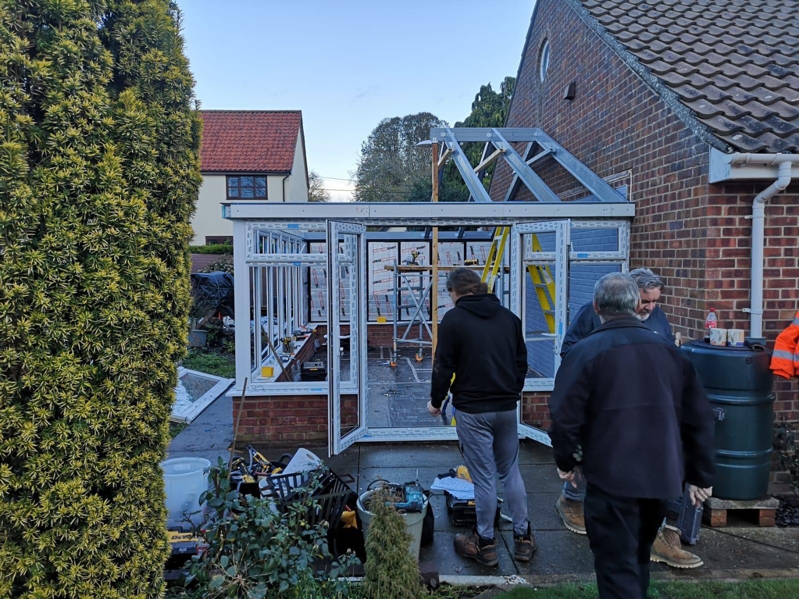 Workers with tools in front of the conservatory that is under construction in garden
