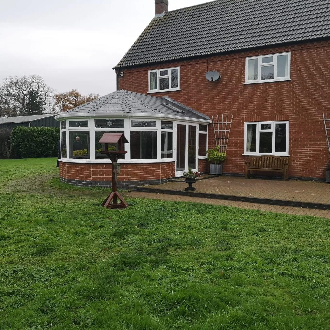 Wide view of tiled conservatory and house with garden.