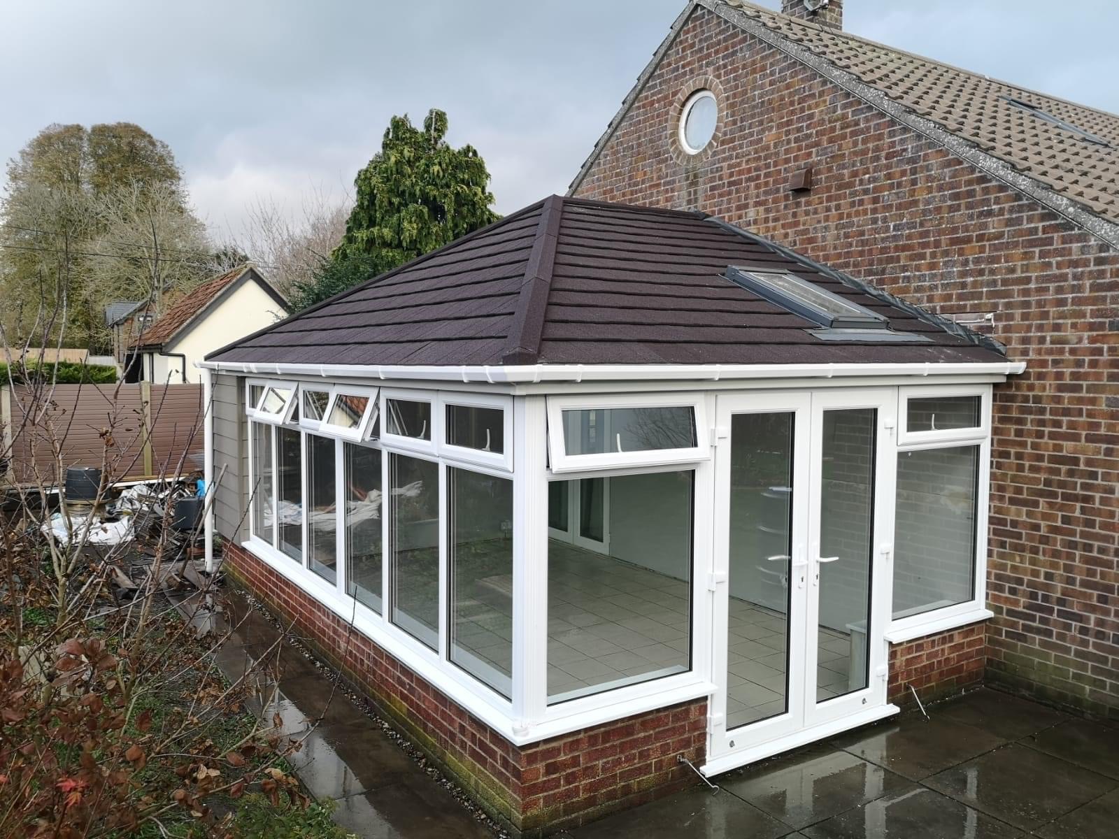 Outside view of Tiled conservatory with white framed uPVC windows and door